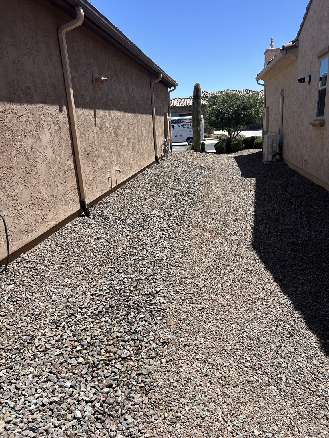 Gravel-covered area beside a home with an AZ Western service van in the distance