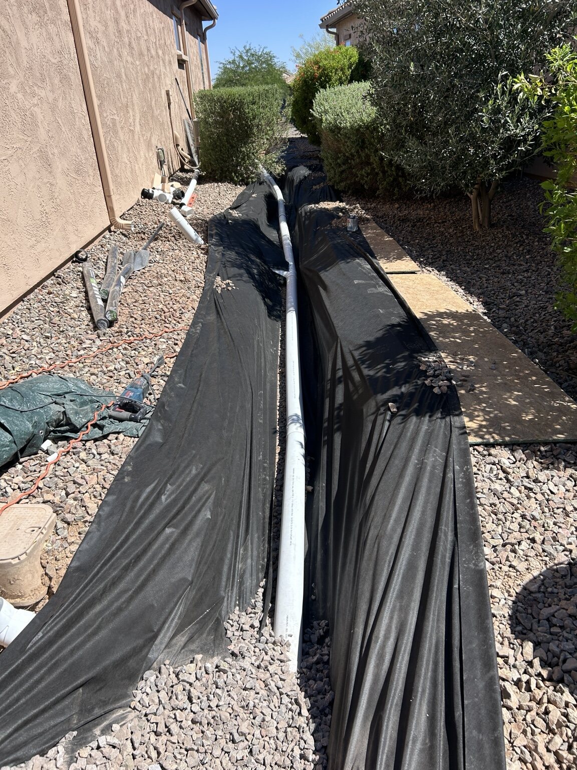 White pipe laid along an open trench beside a home