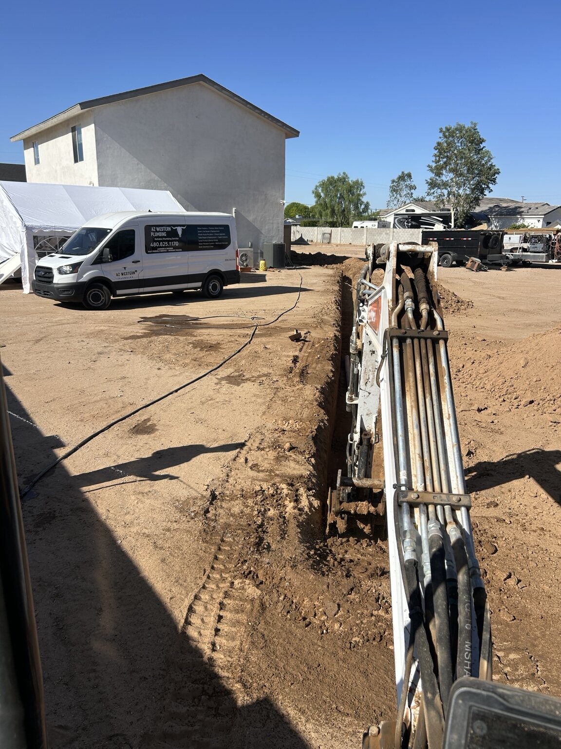 Excavation underway with an AZ Western Plumbing & Air van parked nearby
