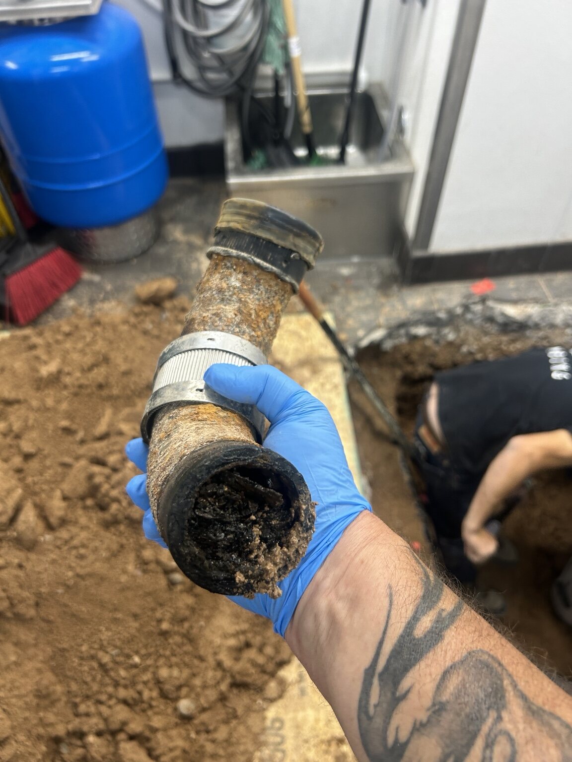 Gloved hand holding a removed pipe section with a buildup inside