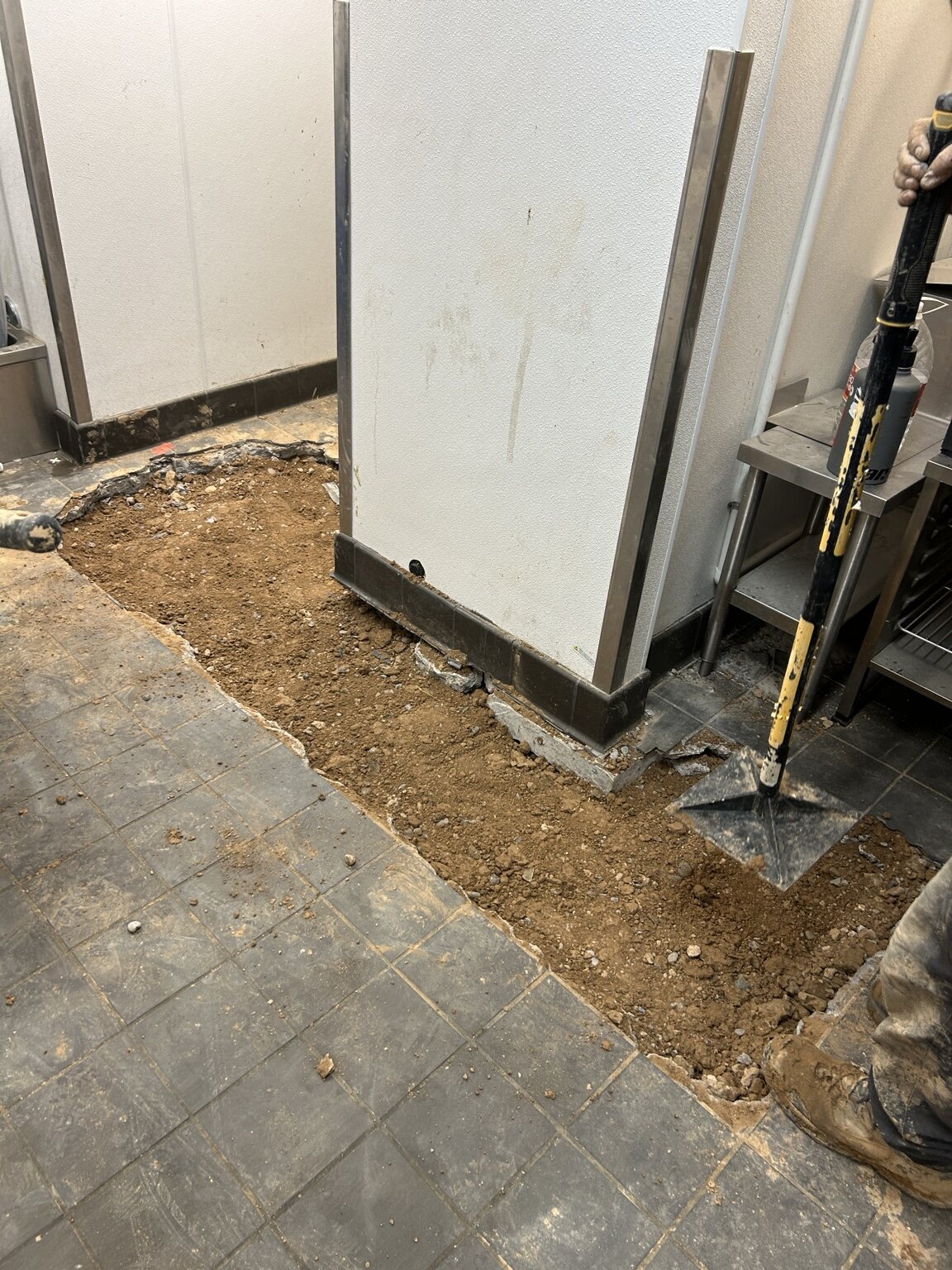 Section of tiled floor opened to expose the ground beneath