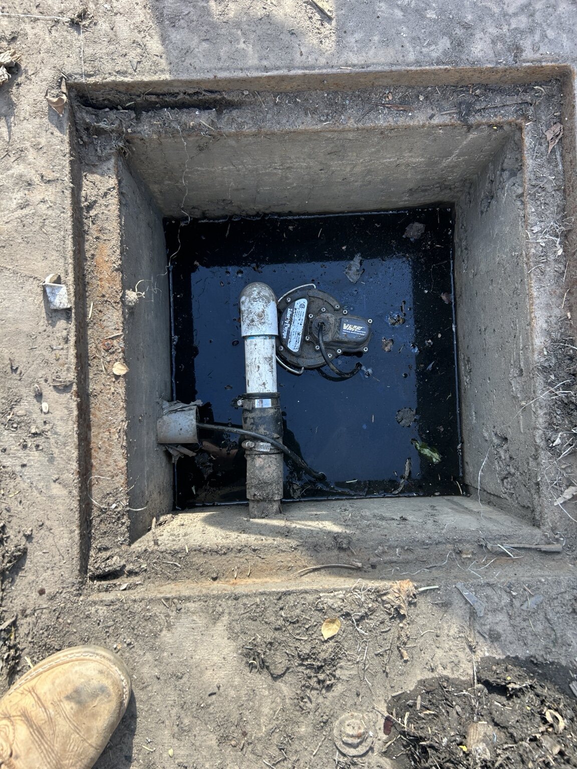 Concrete access pit with pump and piping inside