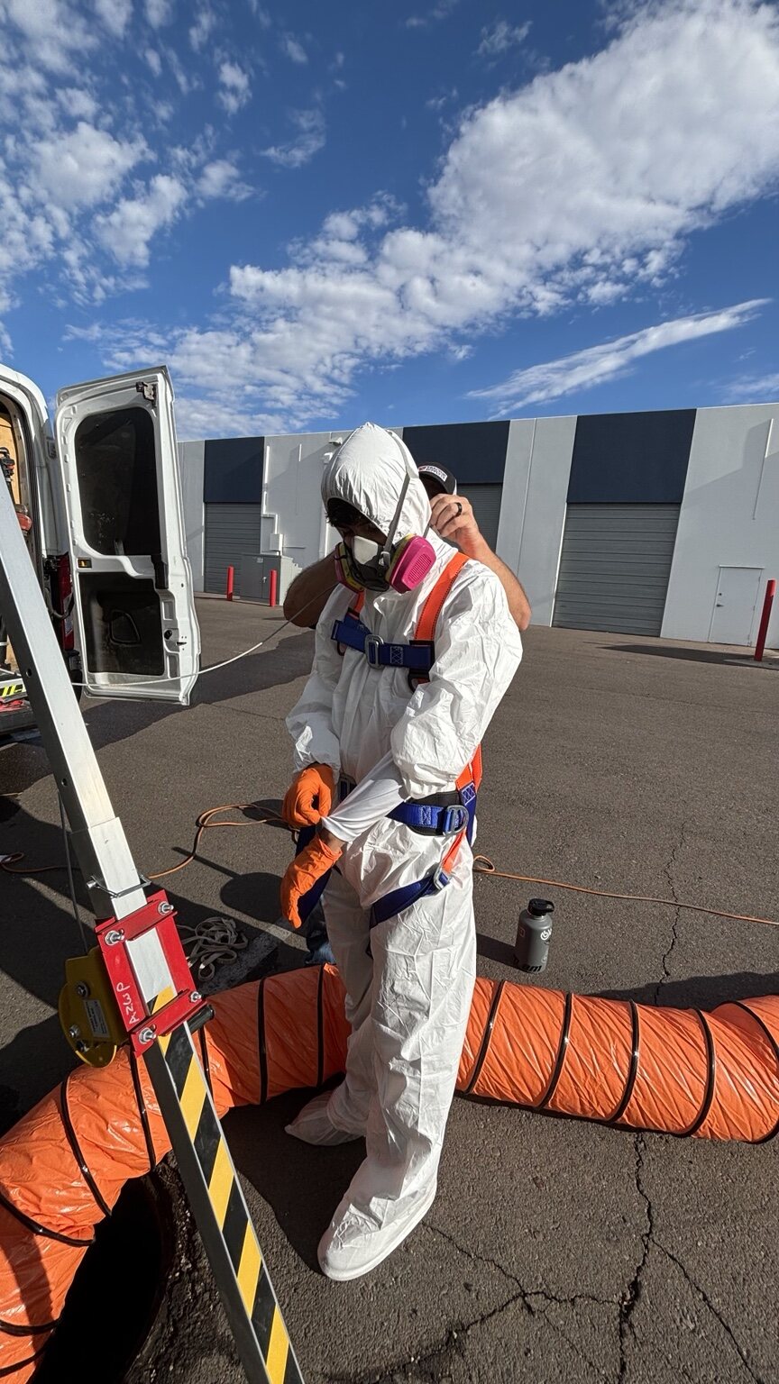 Technician putting on protective suit, respirator, and gloves near a service van