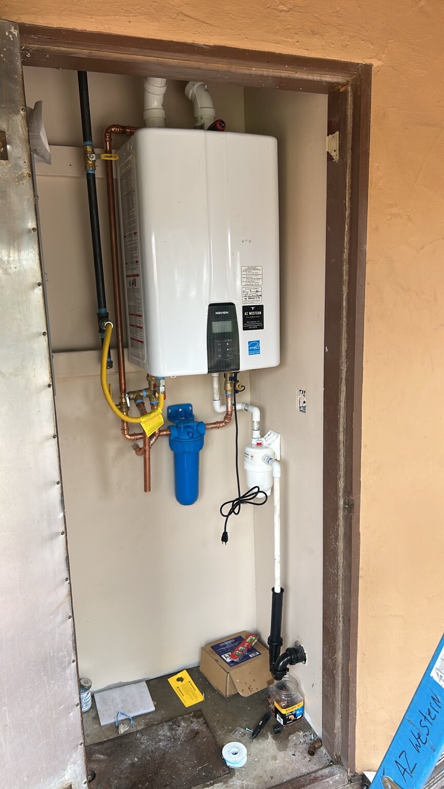 Wall-mounted tankless water heater with AZ Western label, copper pipes, and a blue filter