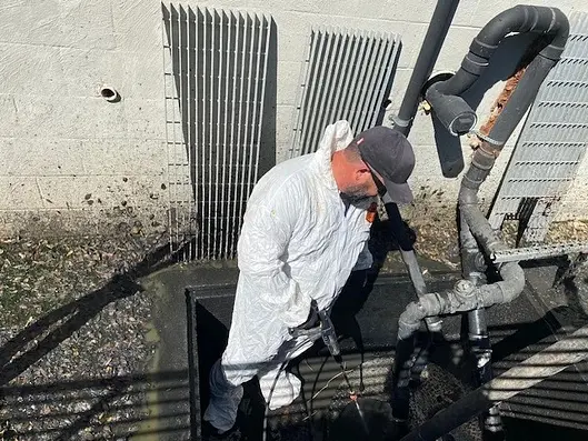 Technician working in a below-grade utility access area